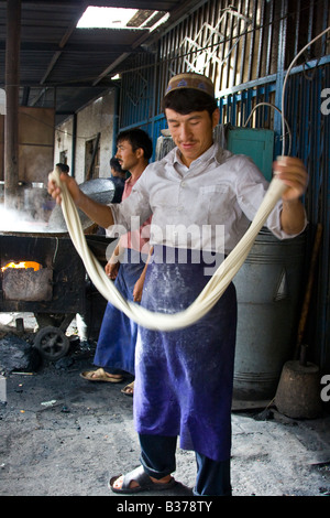 Uyghur Man Making Fresh Laghman le marché du dimanche à nouilles de Kashgar dans la province du Xinjiang en Chine Banque D'Images