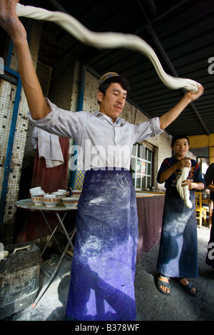 Uyghur Man Making Fresh Laghman le marché du dimanche à nouilles de Kashgar dans la province du Xinjiang en Chine Banque D'Images