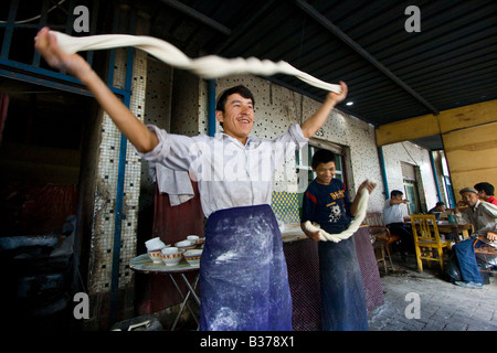 Uyghur Man Making Fresh Laghman le marché du dimanche à nouilles de Kashgar dans la province du Xinjiang en Chine Banque D'Images