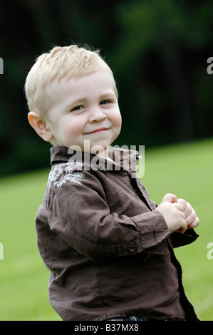 Blonde blue eyed boy playing in field Banque D'Images