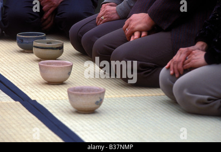 Quatre bols de thé s'asseoir sur le tatami étage pendant que l'homme vous attendez le bon moment pour le boire Banque D'Images