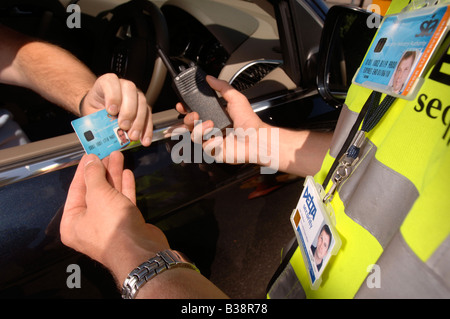 Un garde de sécurité vérifie un badge d'IDENTIFICATION à la guérite de sécuriser les lieux UK Banque D'Images