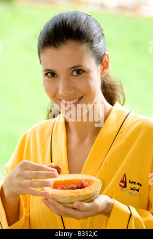 Junge Frau isst frissen vágott kalódás gyertyán Obst, Portrait, jeune femme manger des fruits Banque D'Images