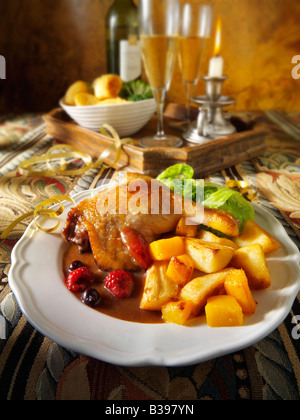 Cuisse de canard au jambon rôti servie avec une sauce aux fruits d'hiver, des pommes de terre rôties et des légumes dans un cadre festif Banque D'Images