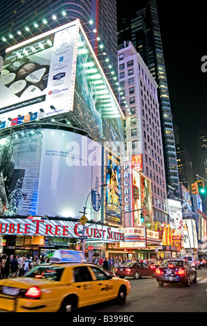 NEW YORK CITY, New York, États-Unis — Une scène nocturne animée de Times Square, l'intersection emblématique de Midtown Manhattan, déborde d'activité. Les taxis jaunes naviguent à travers les rues bondées, leur couleur distinctive se démarquant sur la toile de fond des panneaux lumineux au néon, des panneaux d'affichage massifs, et des écrans LED. Des foules de piétons, touristes et habitants, remplissent les trottoirs et les passages, incarnant l'énergie de «la ville qui ne dort jamais». Banque D'Images