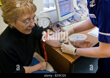 Femme de 60 ans ayant de sang par des infirmières en cabinet médical. Banque D'Images