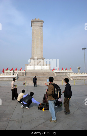 Les touristes se lever et aller de l'avant devant le monument du héros des habitants de la place Tiananmen à Pékin, Chine Banque D'Images