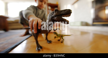 Tyrannosaurus rex modèle dans les mains de six ans de manger un autre jouet d'un dinosaure Velociraptor Banque D'Images