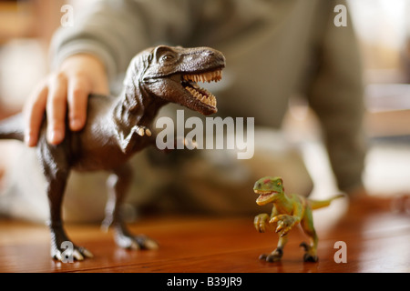 Tyrannosaurus rex modèle dans les mains de six ans de manger un autre jouet d'un dinosaure Velociraptor Banque D'Images