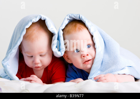 Beau jeune bébé jumeaux aux cheveux rouges se trouvant sur l'avant en vertu douce couverture Banque D'Images