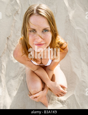 High angle view of redheaded woman sitting on beach wearing bikini à la visionneuse à Banque D'Images