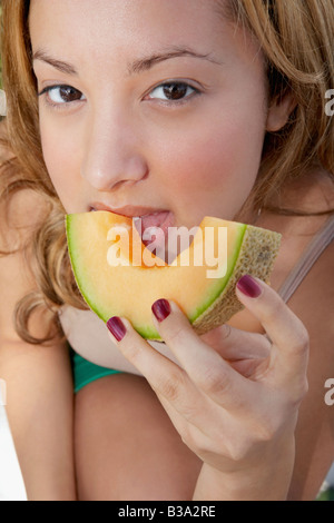 Hispanic woman eating melon slice Banque D'Images
