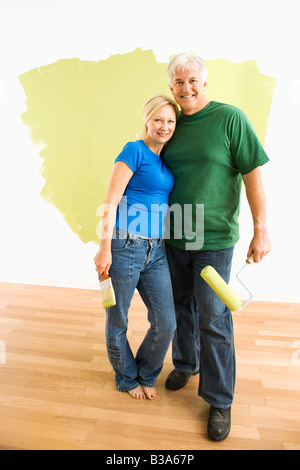 Couple d'âge moyen en face de wall ils sont vert peinture Banque D'Images