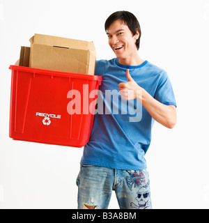 Portrait of young man standing holding recycling bin Banque D'Images