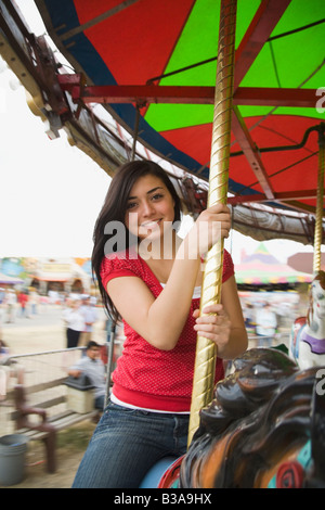 Mixed Race adolescente sur carousel horse Banque D'Images