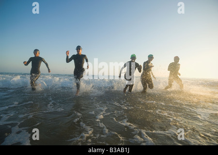 Les nageurs multi-ethnique running in surf Banque D'Images