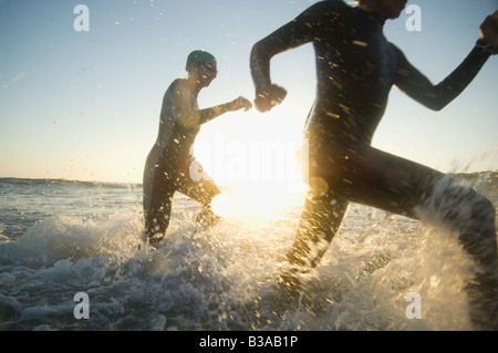 Les nageurs multi-ethnique running in surf Banque D'Images