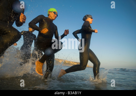 Les nageurs multi-ethnique running in surf Banque D'Images