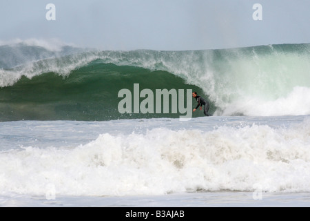 Surfeur sur une grosse vague à Trevaunance Cove, St Agnes, Cornwall, UK Banque D'Images