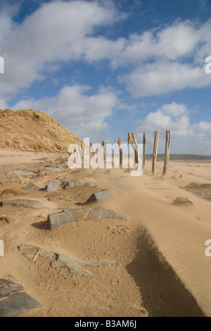 Plage de sable balayé par les vents, des rochers et les apparaux de ligne de clôture montrant l'érosion le long d'une plage dans le Devon UK Banque D'Images