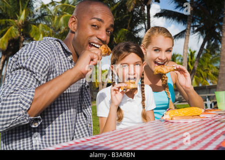 Mixed Race family eating at picnic table Banque D'Images