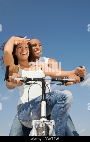 Multi-ethnic couple sitting on bicycle Banque D'Images