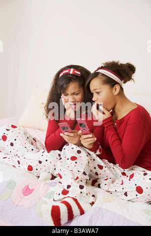 African twin sisters looking at cell phones Banque D'Images