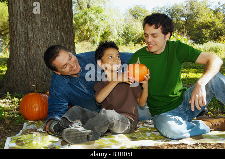La famille multi-ethnique avec des citrouilles under tree Banque D'Images