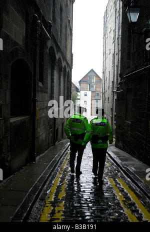 Les agents de police masculins et féminins marchant dans un proche dans la pluie torrentielle de Royal Mile, Édimbourg, Écosse, Royaume-Uni, Europe Banque D'Images