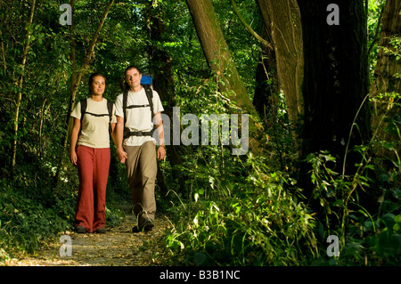 Jeune couple avec sacs à dos randonnée dans un chemin à travers le bois des forêts tenant la main près de Bologne Italie Banque D'Images