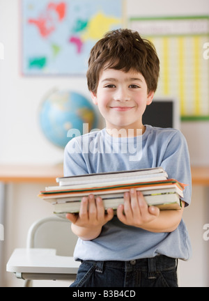 Hispanic boy holding pile de livres d'école Banque D'Images