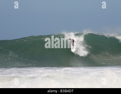 Surfeur sur une grosse vague à Trevaunance Cove, St Agnes, Cornwall, UK Banque D'Images