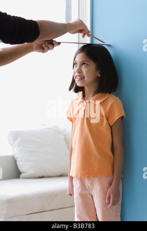 Asian girl ayant hauteur mesurée sur le mur Banque D'Images