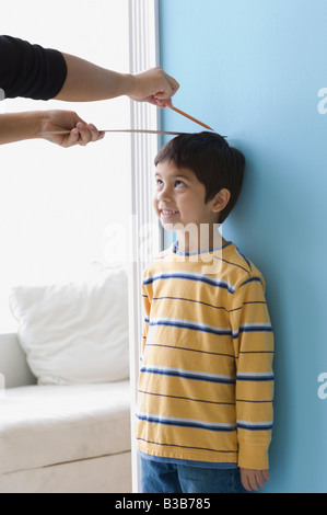 Asian boy having hauteur mesurée sur le mur Banque D'Images