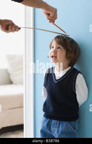 Asian boy having hauteur mesurée sur le mur Banque D'Images