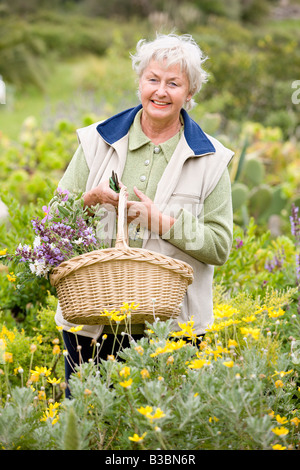 Portrait de femme en prairie, fleurs de collecte Banque D'Images