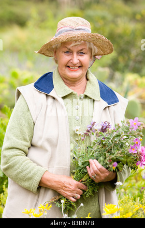 Portrait de femme en prairie, fleurs de collecte Banque D'Images