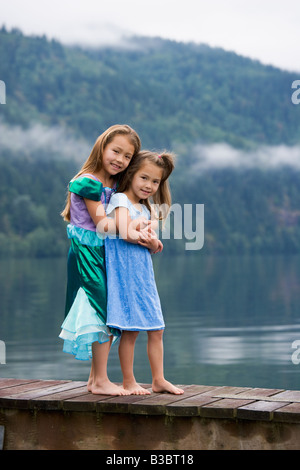 Asian sisters hugging on dock Banque D'Images