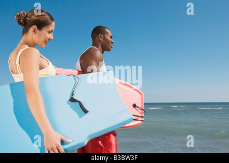 Multi-ethnic couple holding bodyboard Banque D'Images