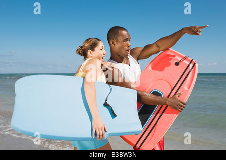 Multi-ethnic couple holding bodyboard Banque D'Images