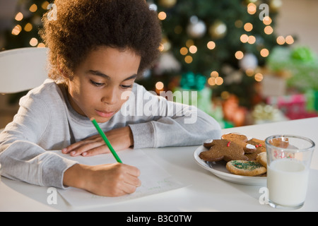 Mixed Race boy écrit une lettre au Père Noël Banque D'Images