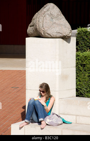 Young Woman Reading book sur le parvis de la British Library. Euston Road, Londres, Angleterre Banque D'Images