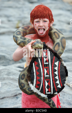 Kenya, Masai Mara National Reserve. Jeune garçon sur safari dans le Masai Mara, vêtu comme un guerrier Massaï et jouer avec un jouet serpent (MR). Banque D'Images