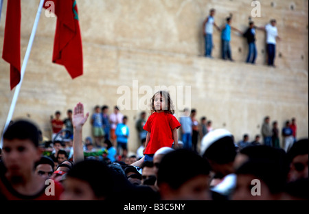 Maroc, Fes. Sur la toile de fond des anciens remparts de Fès, une jeune fille se distingue dans la foule à un concert gratuit à la place Boujloud pendant le Festival de Fès des Musiques Sacrées du Monde. Banque D'Images