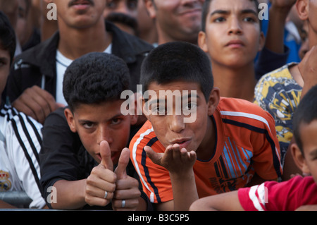 Maroc, Fes. Deux garçons dans la foule à un concert au cours du Festival de Fès des Musiques Sacrées du Monde souffler des baisers. Banque D'Images