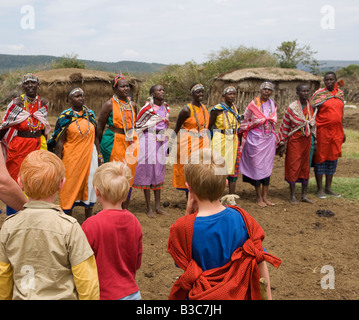 Kenya, Masai Mara National Reserve. Les enfants sur une famille visite safari un Masaï manyatta ou village juste en dehors de la réserve. Banque D'Images