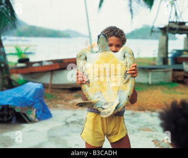Les Seychelles. Garçon tenant une tortue. Banque D'Images