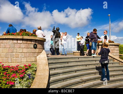 Les touristes ayant leur photo prise avec l'Eric Morecambe statue en bronze à Morecambe Lancashire England UK Banque D'Images