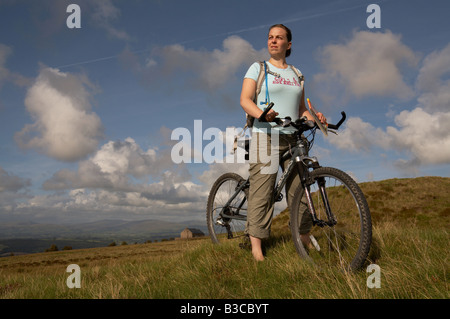 Un cycliste féminine en profitant de la vue d'un parc éolien sur les landes de la forêt de Bowland dans le Lancashire Banque D'Images