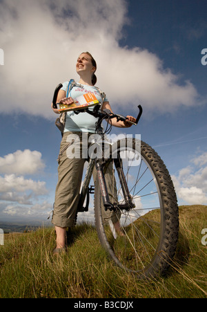 Un cycliste féminine en profitant de la vue d'un parc éolien sur les landes de la forêt de Bowland dans le Lancashire Banque D'Images